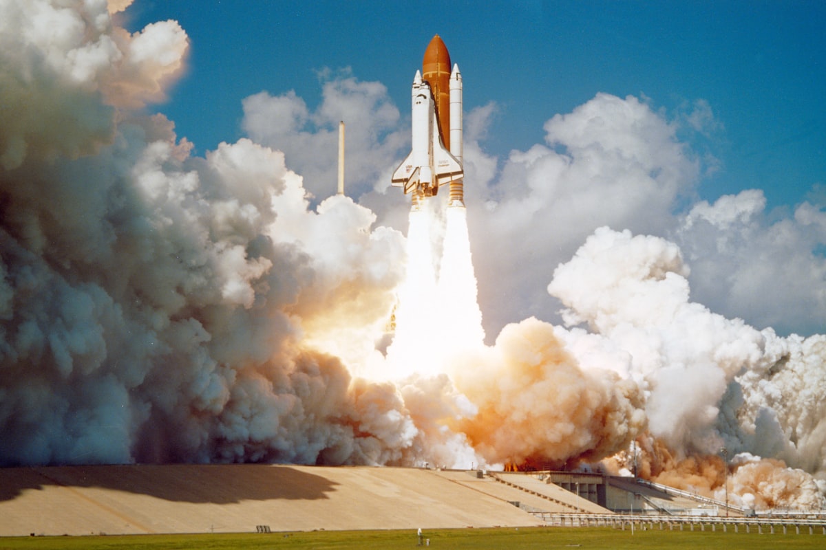 Space shuttle lifting off from the launch pad in billowing clouds of smoke